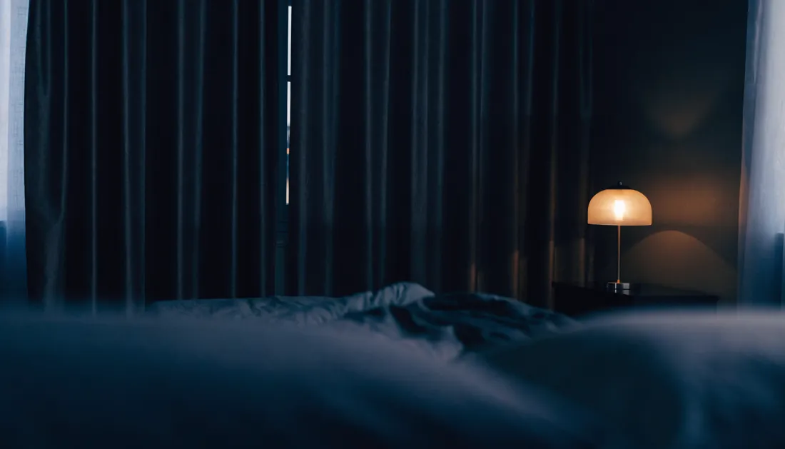 Heavy blackout curtains drawn across a bedroom window with faint light at the edges