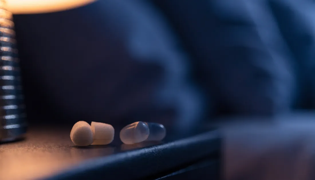 Foam and silicone sleep earplugs on a dark nightstand