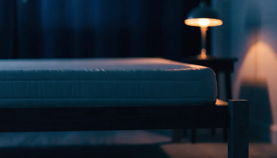 A supportive mattress on a low bed frame in a calm dark bedroom
